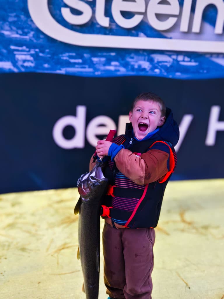 Excited young angler holding a steelhead at the derby
